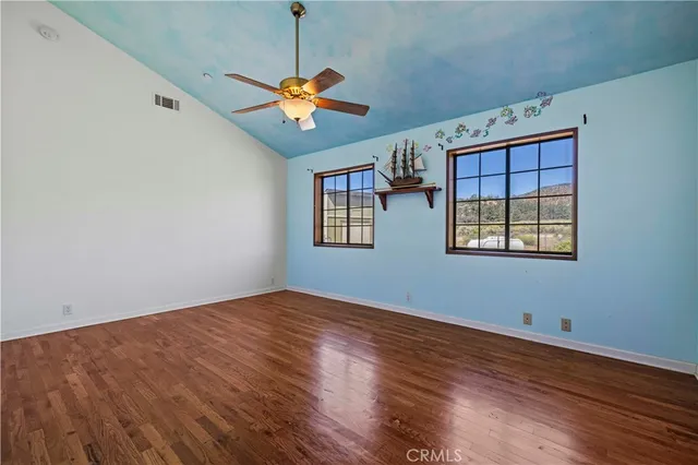 a view of an empty room with window and wooden floor