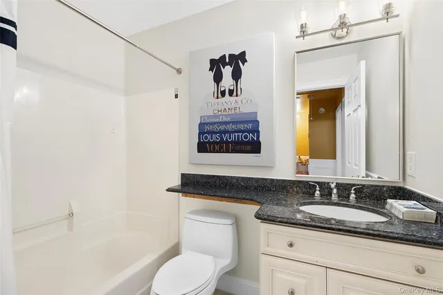 a bathroom with a granite countertop sink toilet and painting on the wall