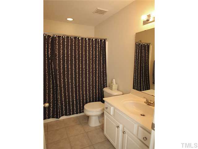 7813 Silverthread Lane Raleigh, NC 27617 - Photo 9 of 25 a bathroom with a sink a toilet a mirror and shower curtain