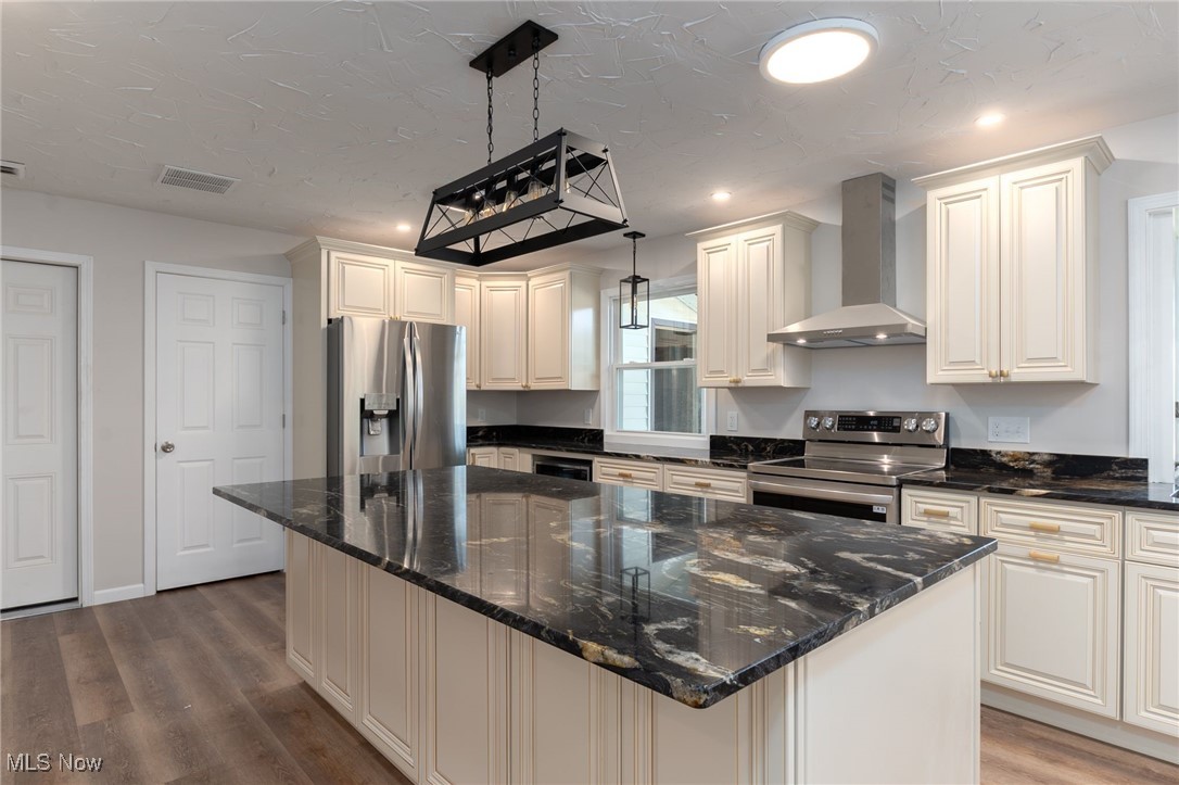 13295 Sperry Road Chesterland, OH 44026 - Photo 13 of 35 Kitchen with wall chimney exhaust hood, hardwood / wood-style floors, appliances with stainless steel finishes, and pendant lighting