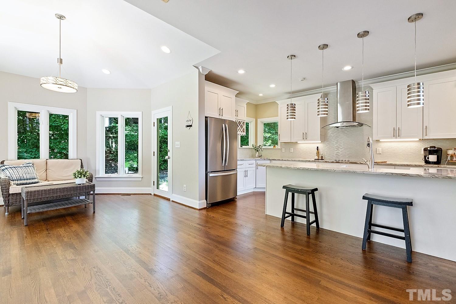 100 Greyfriars Lane Cary, NC 27518 - Photo 20 of 71 a kitchen with stainless steel appliances granite countertop a stove a refrigerator a kitchen island a dining table and chairs with wooden floor