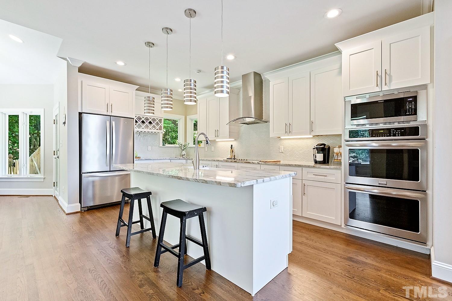 100 Greyfriars Lane Cary, NC 27518 - Photo 25 of 71 a kitchen with stainless steel appliances granite countertop a refrigerator a stove a sink a dining table and chairs with wooden floor