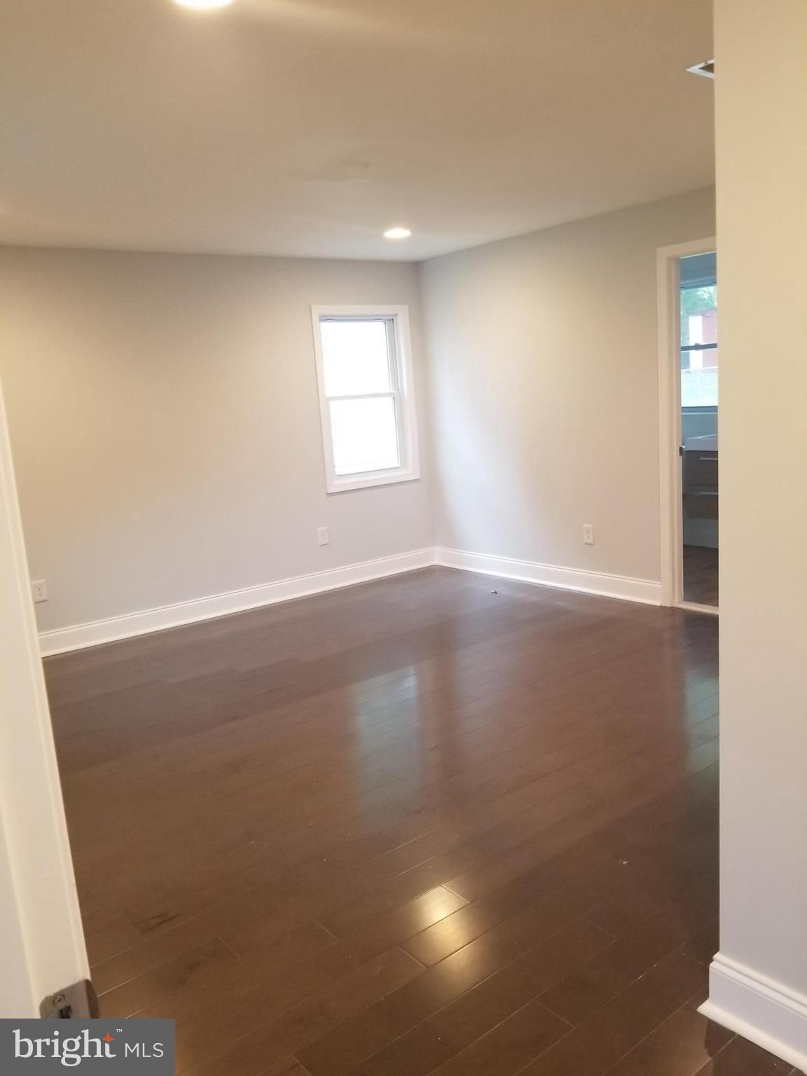 6828 Campfield Road Baltimore, MD 21207 - Photo 11 of 26 an empty room with wooden floor and windows