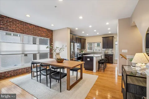 a kitchen with stainless steel appliances granite countertop a stove top oven a sink dishwasher a dining table and chairs with wooden floor