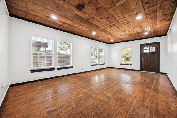a view of an empty room with window and wooden floor