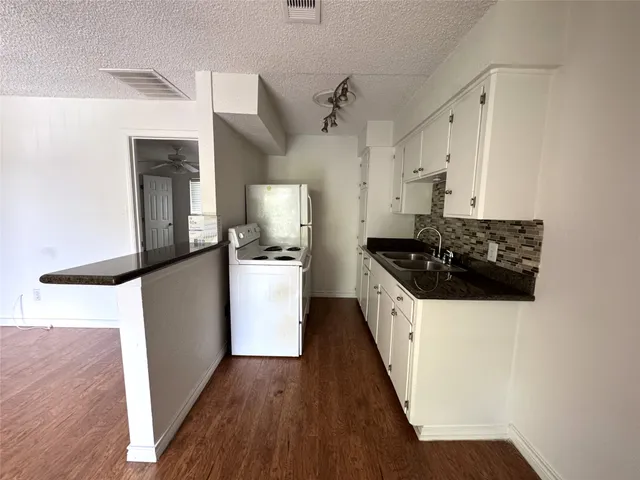 a kitchen with a refrigerator a stove and wooden floor
