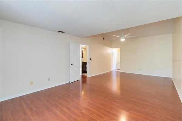 a view of empty room with wooden floor and fan
