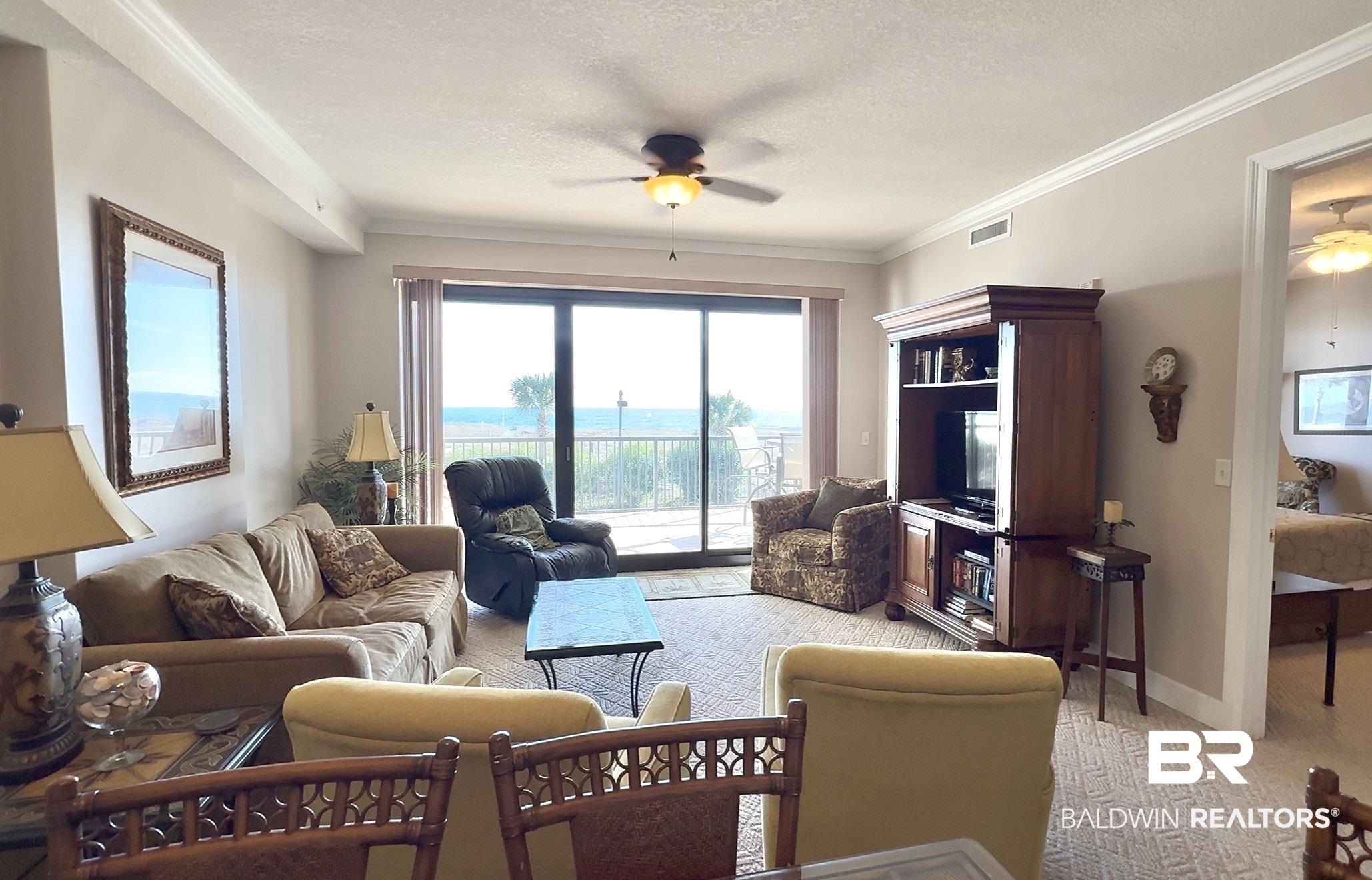 27284 Gulf Road, Unit 212 Orange Beach, AL 36561 - Photo 3 of 35 Living room with ceiling fan, light carpet, crown molding, a textured ceiling, and plenty of natural light