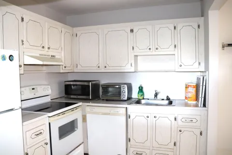 a kitchen with white cabinets and white appliances