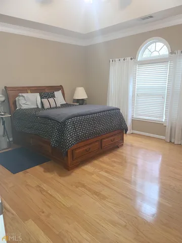a spacious bedroom with a bed and wooden floor