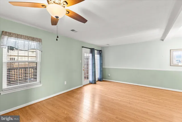 a view of an empty room with window and wooden floor