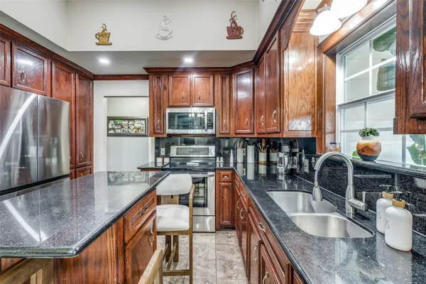 a kitchen with stainless steel appliances granite countertop a sink window and cabinets