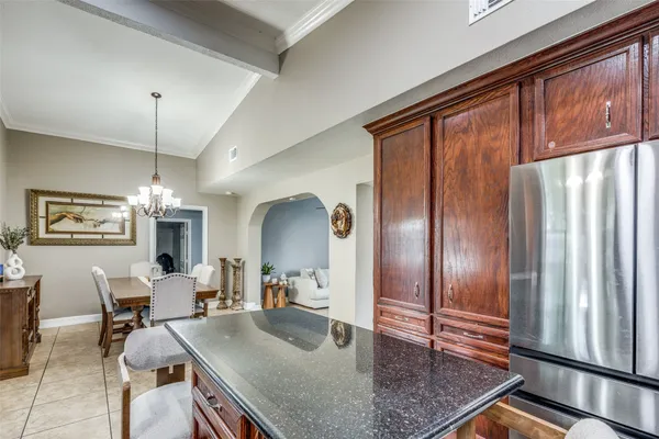 a kitchen with stainless steel appliances granite countertop a refrigerator a stove a sink dishwasher a dining table and chairs with wooden floor
