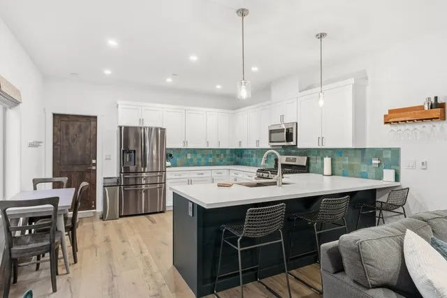 a kitchen with stainless steel appliances kitchen island granite countertop a table chairs stove and refrigerator