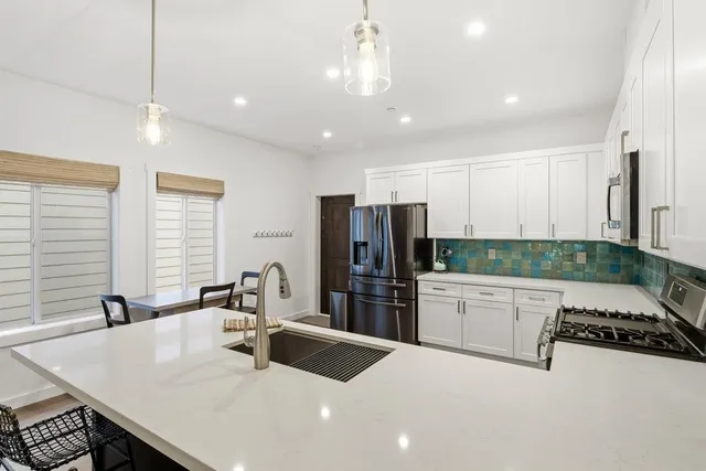 a kitchen with stainless steel appliances a sink a stove a refrigerator and cabinets