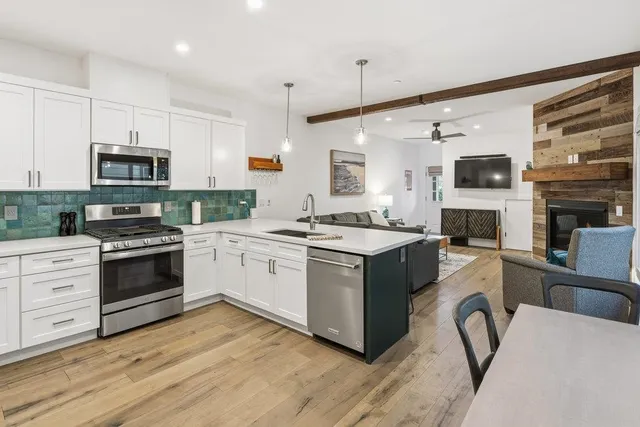 a kitchen with a stove top oven a sink dishwasher a dining table and chairs with wooden floor