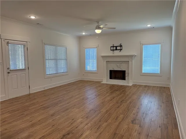 an empty room with wooden floor fireplace and windows