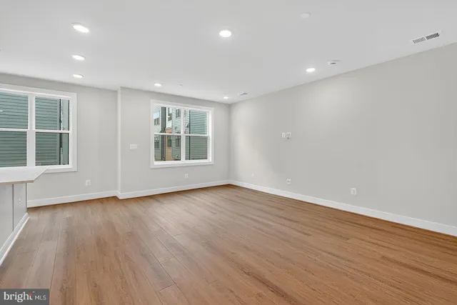 an empty room with wooden floor and windows