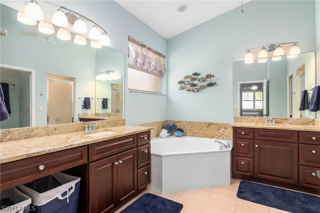 9036 Springview Loop Estero, FL 33928 - Photo 17 of 32 a spacious bathroom with a granite countertop sink a large mirror and bathtub