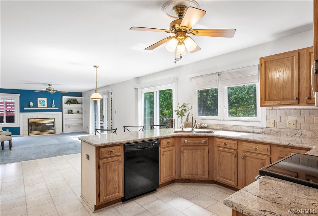 5826 Spinnaker Cove Road Midlothian, VA 23112 - Photo 14 of 38 Kitchen with black dishwasher, light tile flooring, light stone counters, brown cabinets, a healthy amount of sunlight, hanging light fixtures, backsplash, and ceiling fan
