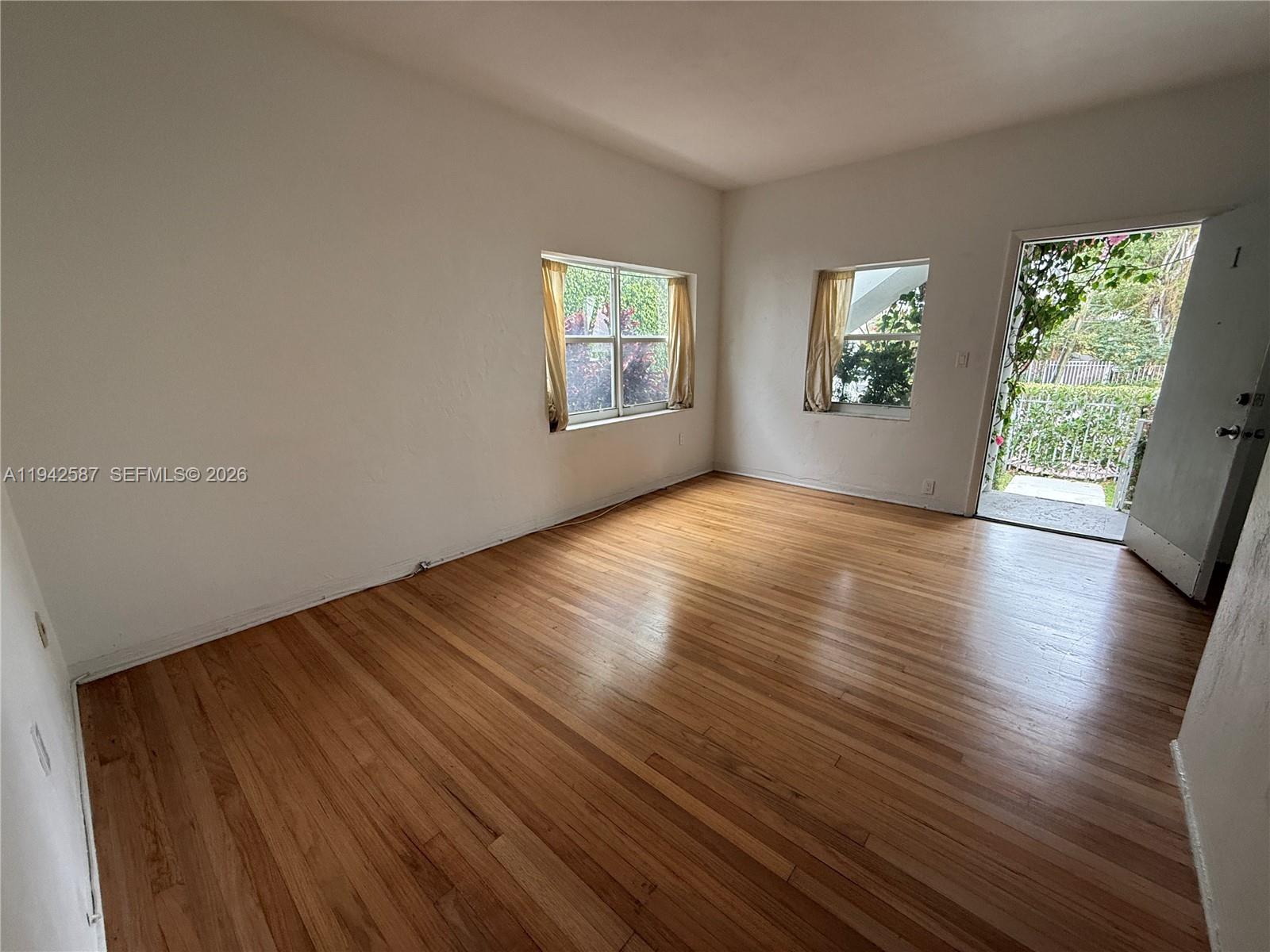 1011 9th Street, Unit 1 Miami Beach, FL 33139 - Photo 4 of 15 a view of an empty room with wooden floor and a window
