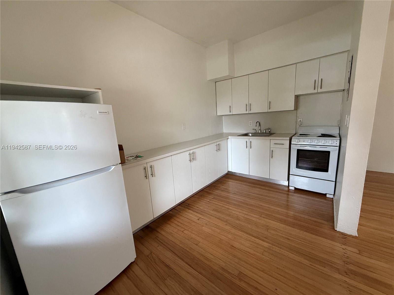 1011 9th Street, Unit 1 Miami Beach, FL 33139 - Photo 6 of 15 a kitchen with stainless steel appliances a refrigerator and wooden floor