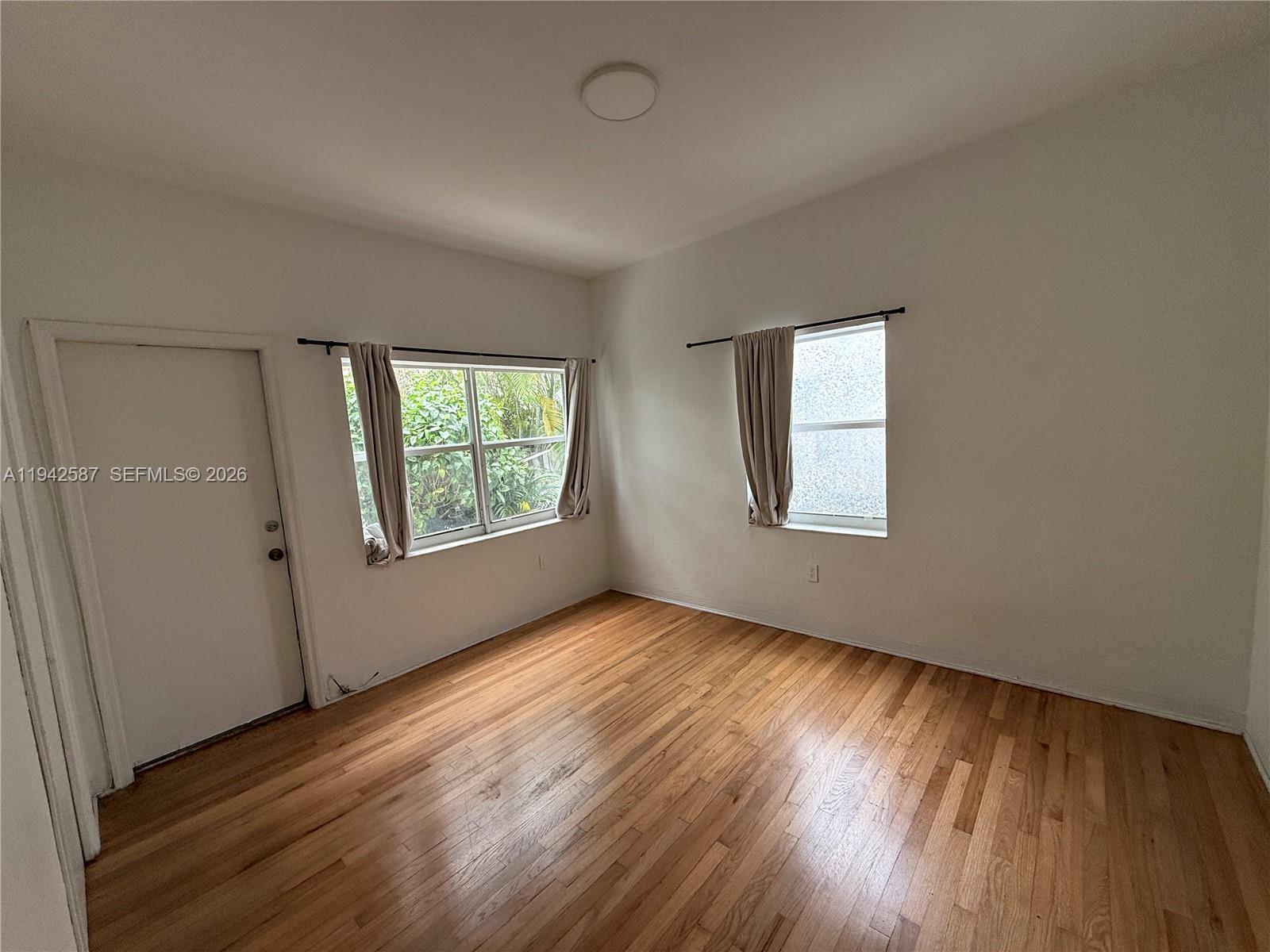 1011 9th Street, Unit 1 Miami Beach, FL 33139 - Photo 10 of 15 an empty room with wooden floor and windows