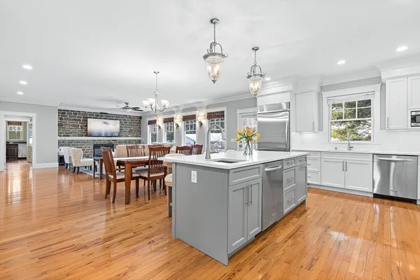 a kitchen with stainless steel appliances granite countertop hardwood floor sink stove dining table and chairs