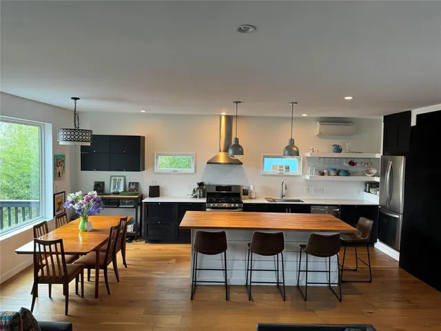 a kitchen with stainless steel appliances kitchen island granite countertop a table chairs stove and refrigerator