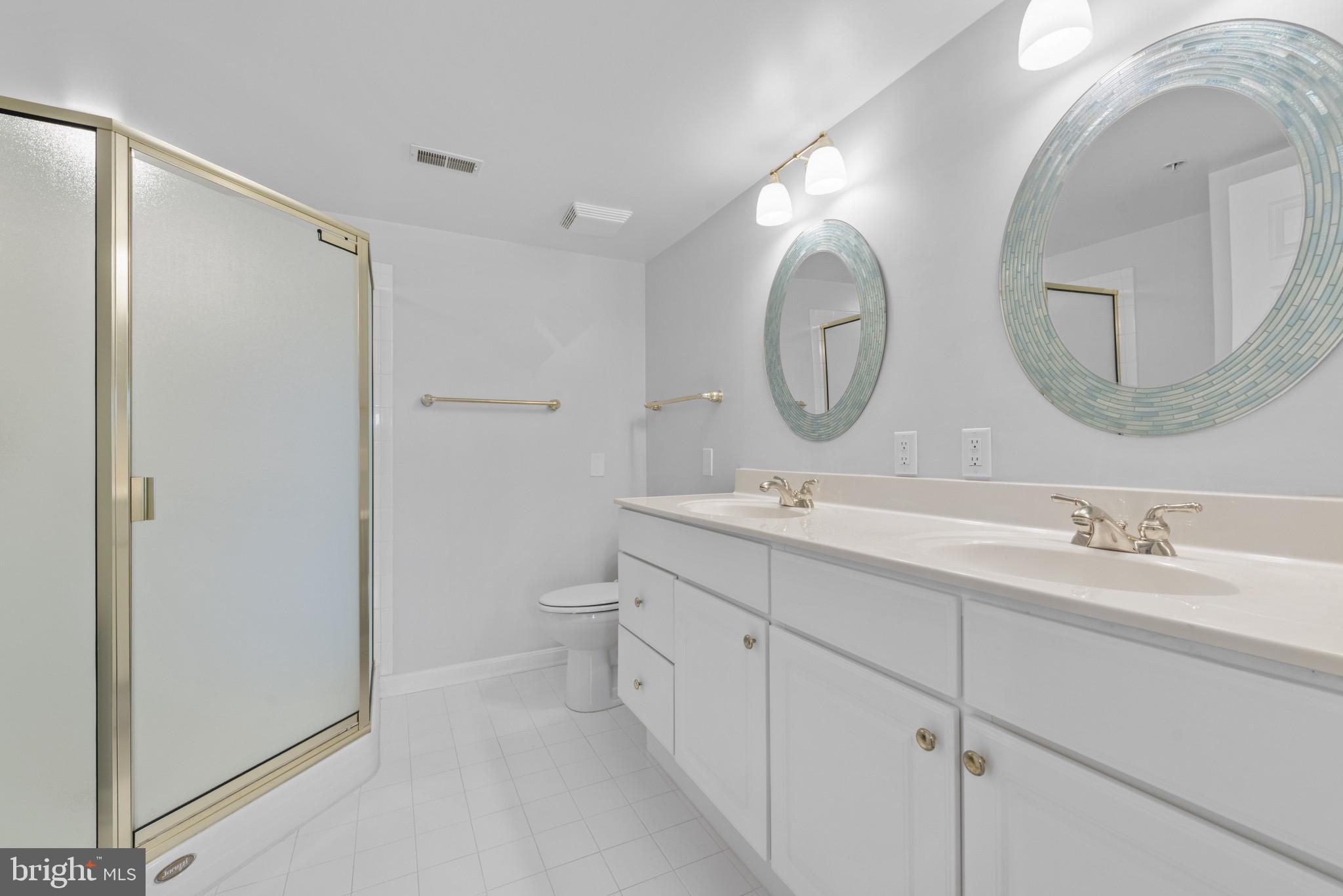 12240 Roundwood Road, Unit 704 Lutherville-Timonium, MD 21093 - Photo 13 of 22 a bathroom with a double vanity sink mirror and a toilet
