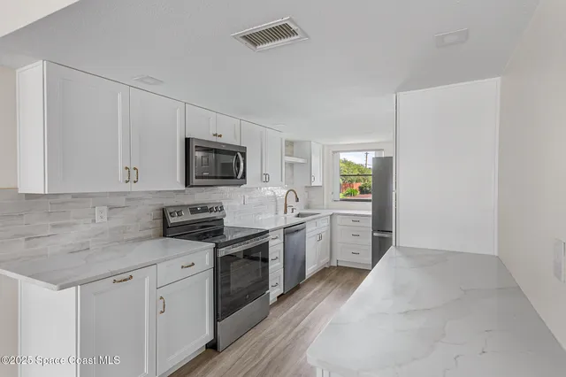 a kitchen with white cabinets and stainless steel appliances