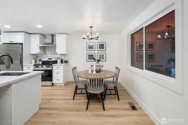 a kitchen with stainless steel appliances granite countertop a dining table chairs and a refrigerator