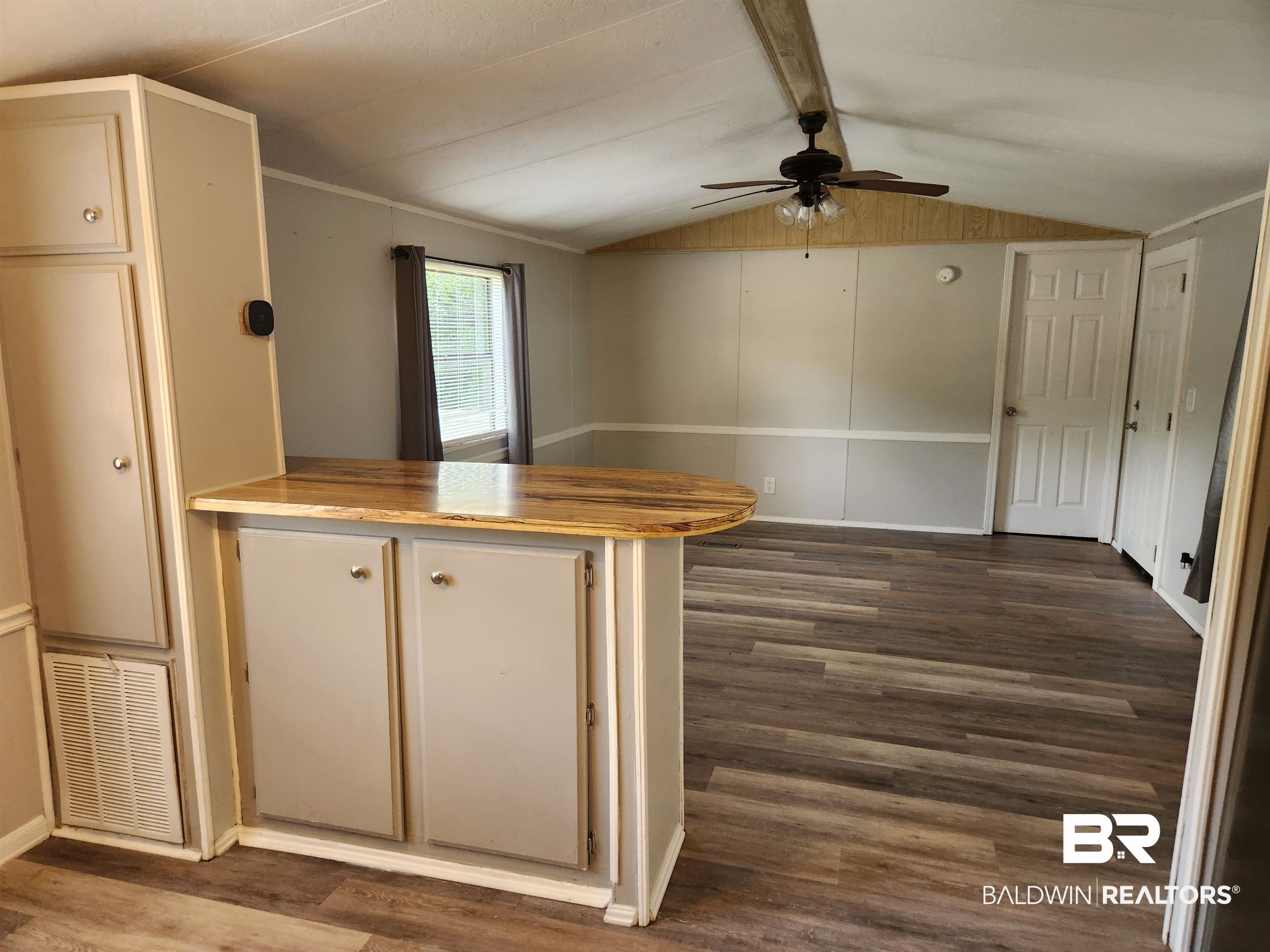 23051 Fritz Lane Foley, AL 36535 - Photo 21 of 26 Open-concept living area featuring wood-finish flooring, a ceiling fan with light fixture, light gray walls, and a built-in breakfast bar with wood-finish countertop