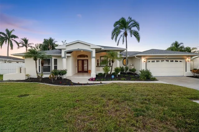 a front view of a house with a garden and palm trees