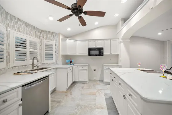 a kitchen with stainless steel appliances granite countertop a dining table chairs refrigerator and microwave