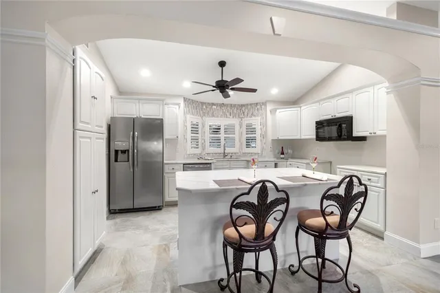 a kitchen with stainless steel appliances granite countertop a dining table chairs refrigerator and microwave