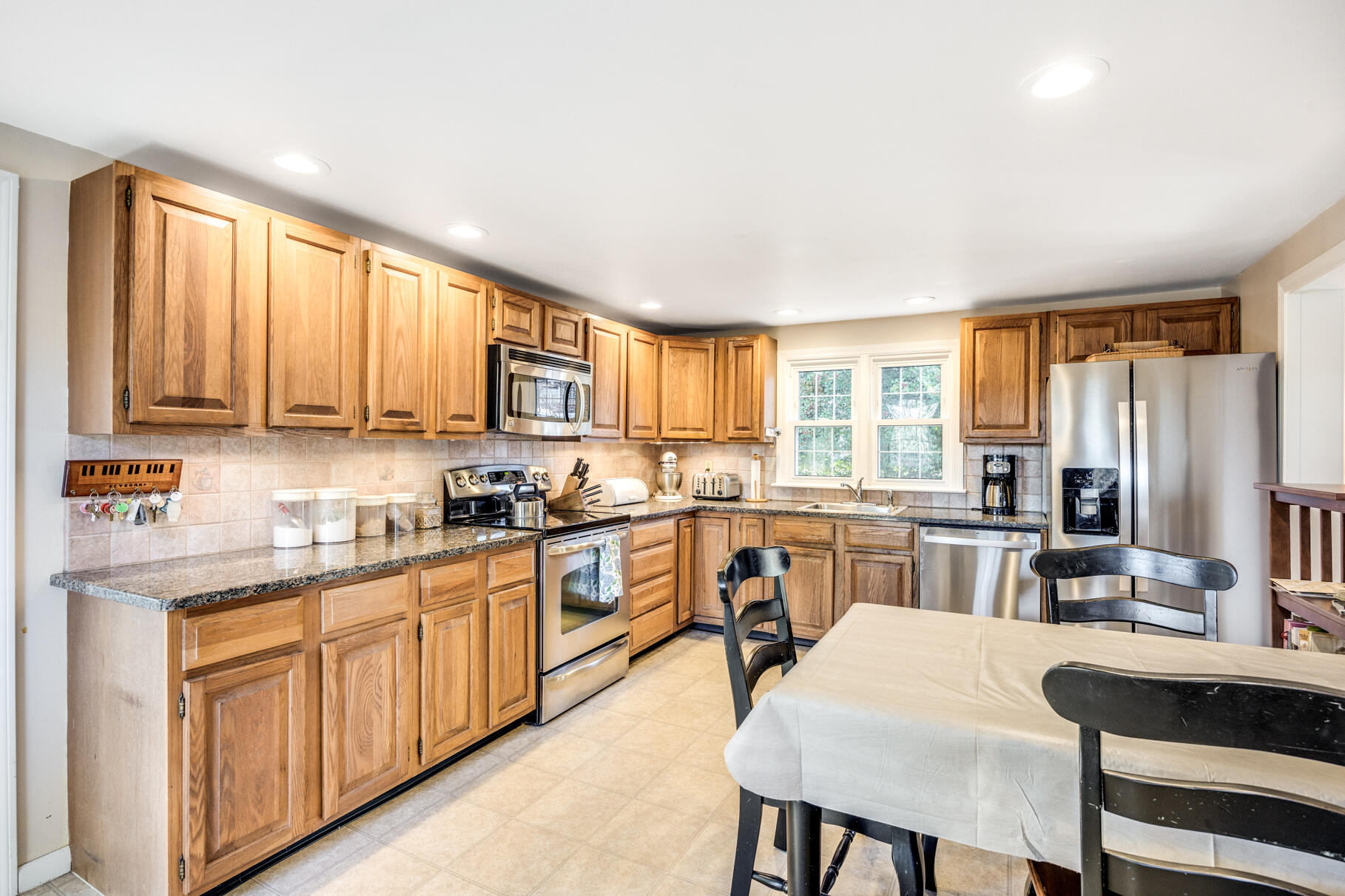 38 Rainbow Way Harwich, MA 02645 - Photo 13 of 50 a large kitchen with stainless steel appliances granite countertop a stove a sink dishwasher a dining table and chairs with wooden floor