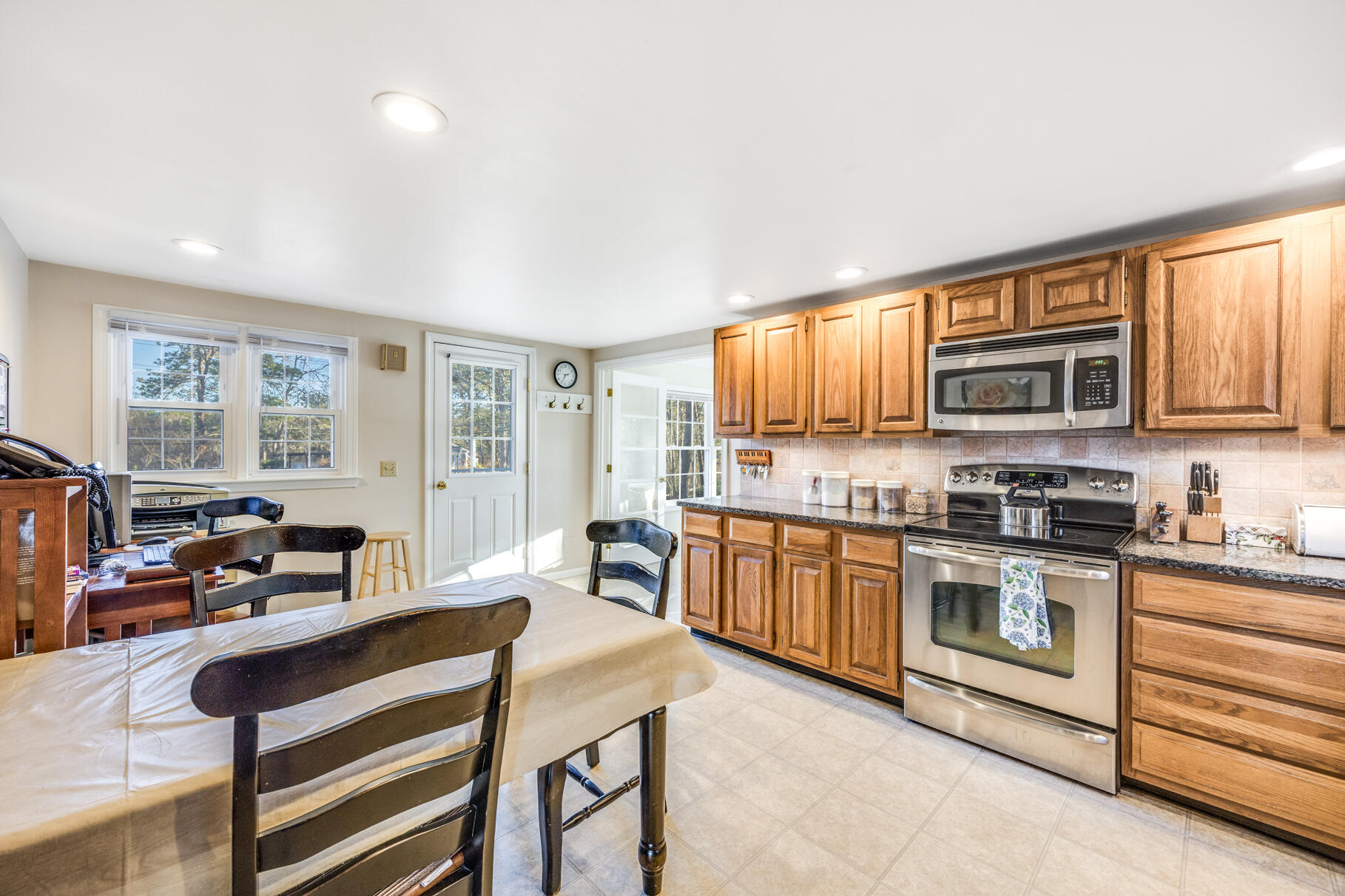 38 Rainbow Way Harwich, MA 02645 - Photo 14 of 50 a kitchen with stainless steel appliances granite countertop a stove top oven a sink dishwasher a dining table and chairs with wooden floor