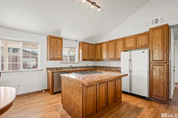 a kitchen with a stove a refrigerator and wooden floor