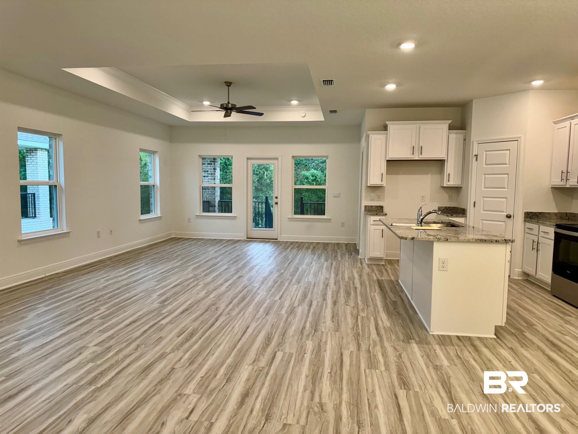 12884 Grand Rpds Road Fairhope, AL 36532 - Photo 13 of 32 Kitchen featuring a kitchen island with sink, light wood-type flooring, a healthy amount of sunlight, and stone countertops