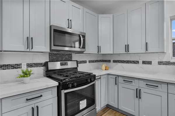 a kitchen with granite countertop white cabinets stainless steel appliances and a wooden floor