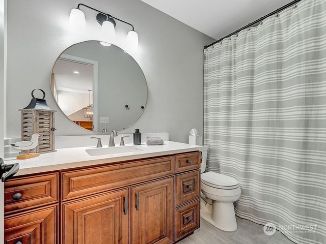 a bathroom with a toilet sink vanity and mirror