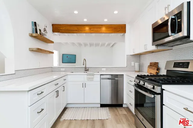 a kitchen with stainless steel appliances granite countertop a stove a sink and a microwave