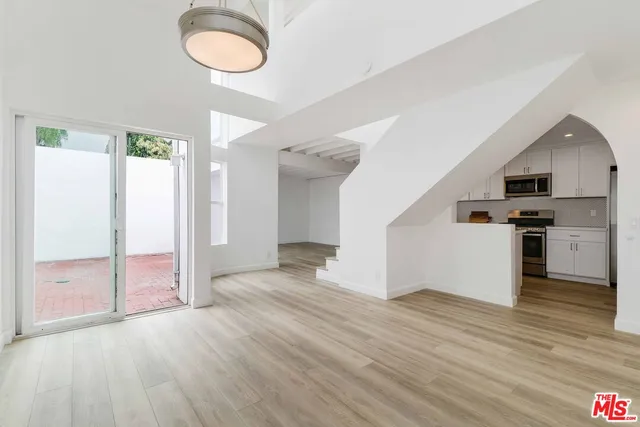 an empty room with wooden floor sink and kitchen view