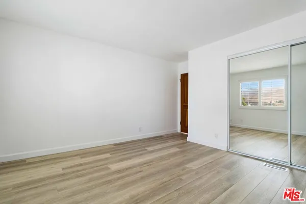 an empty room with wooden floor and mirror