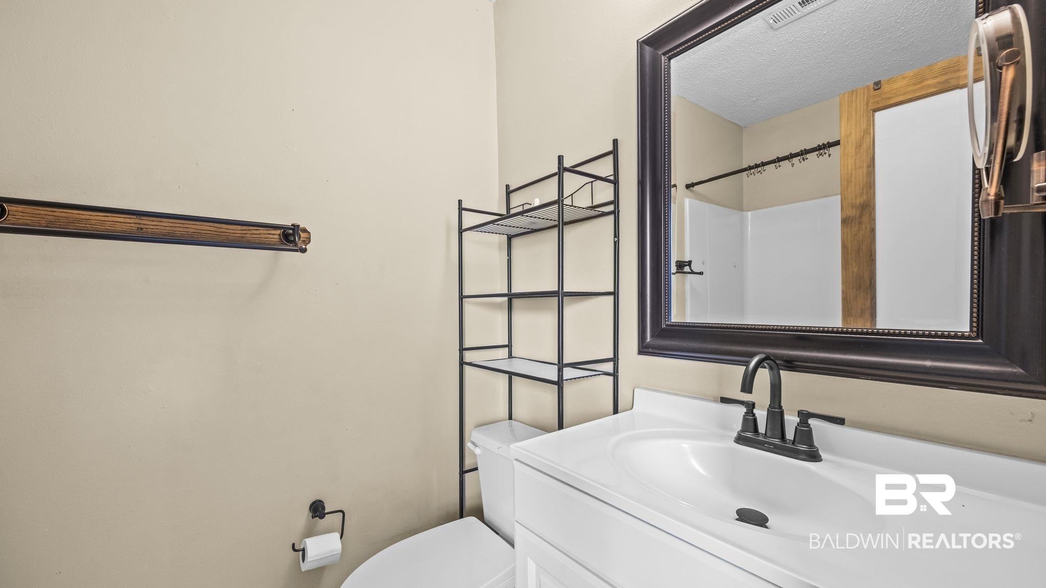 15096 Highland Circle Foley, AL 36535 - Photo 29 of 52 Bathroom featuring a white vanity with integrated sink, dark-finished faucet, and large framed mirror