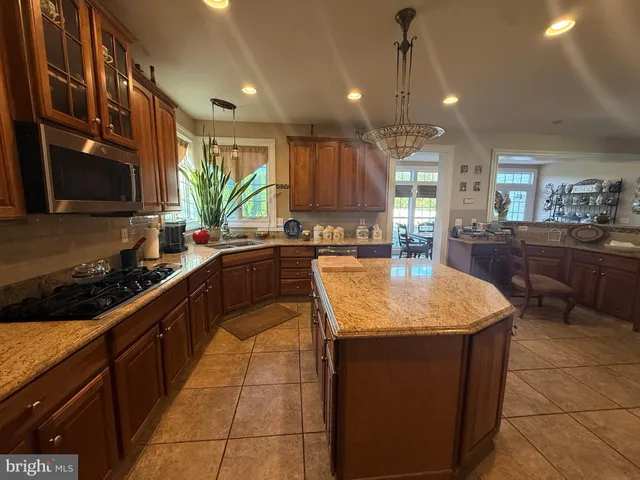 a kitchen with kitchen island granite countertop a sink a counter top space appliances and cabinets