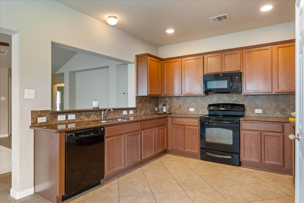 1810 Laminar Creek Road Cedar Park, TX 78613 - Photo 12 of 25 a kitchen with stainless steel appliances granite countertop a stove sink and cabinets