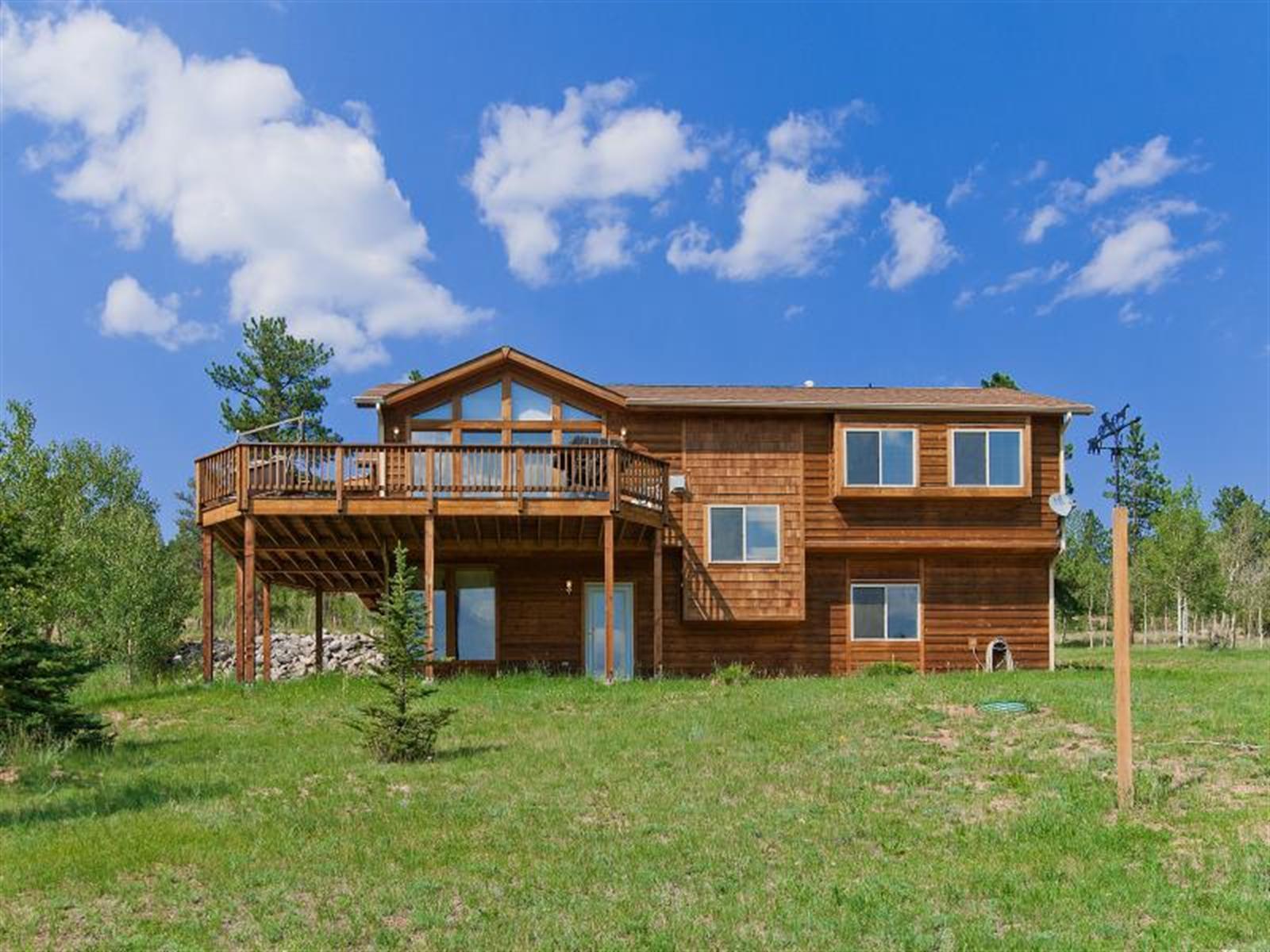 a view of house with a big yard and large trees