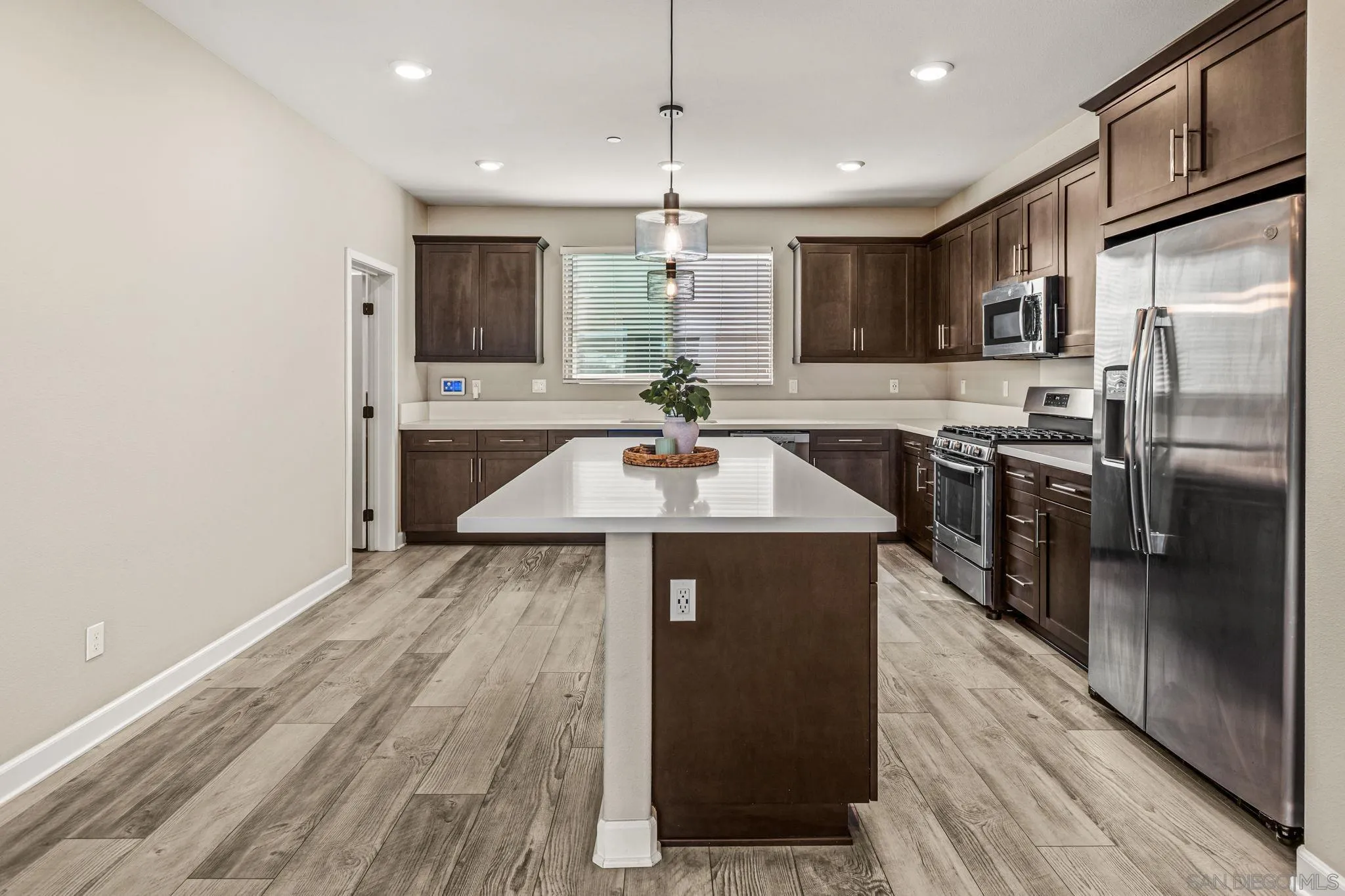 1922 Strata Street, Unit 5 Chula Vista, CA 91915 - Photo 4 of 45 a kitchen with stainless steel appliances a dining table chairs refrigerator and microwave